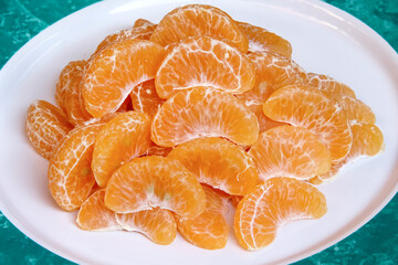 Tangerine slices or mandarin orange fruit  in white plate close up background