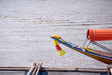 Colorful flower garland hanging on tied of a long tailed boat