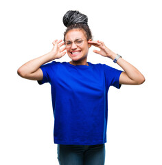 Fototapeta premium Young braided hair african american girl wearing glasses over isolated background covering ears with fingers with annoyed expression for the noise of loud music. Deaf concept.