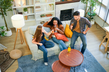 Friends enjoy a relaxed gathering at home, casually chatting and sipping drinks in a cozy living...