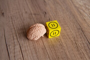 Closeup image of brain model and wooden cube with pause button icon. Rest, relax, take a break...