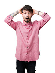 Young handsome man wearing pink shirt over isolated background Crazy and scared with hands on head, afraid and surprised of shock with open mouth