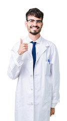 Young professional scientist man wearing white coat over isolated background doing happy thumbs up gesture with hand. Approving expression looking at the camera showing success.