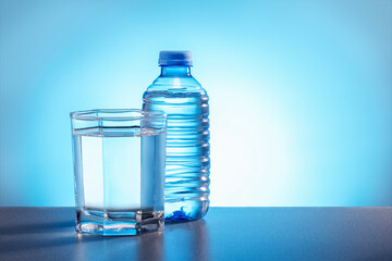 Drink water in a bottle and a glass on blue background with free place for text.