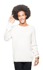 Young african american man with afro hair wearing winter sweater smiling positive doing ok sign...