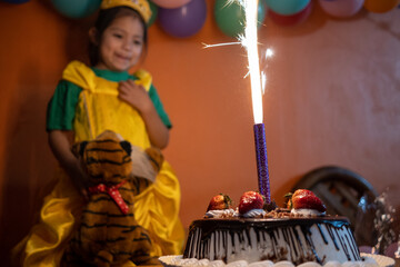 5 year old Mexican girl celebrating her birthday in front of a cake
