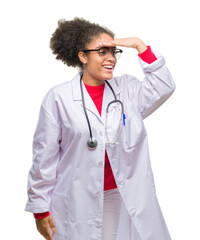 Young afro american doctor woman over isolated background very happy and smiling looking far away with hand over head. Searching concept.