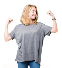Obraz premium Beautiful young woman wearing oversize casual t-shirt over isolated background showing arms muscles smiling proud. Fitness concept.