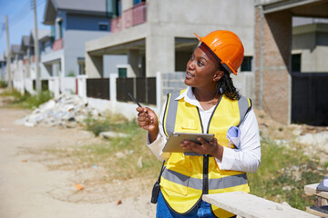 worker or architect working on tablet for home inspection at construction site - obrazy, fototapety, plakaty