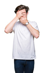 Young handsome man wearing casual white t-shirt over isolated background Covering eyes and mouth with hands, surprised and shocked. Hiding emotion