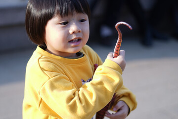 玩具の恐竜の尻尾を持っている子供/ A child holding a toy dinosaur tail