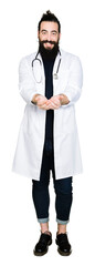 Fototapeta premium Doctor with long hair wearing medical coat and stethoscope Smiling with hands palms together receiving or giving gesture. Hold and protection