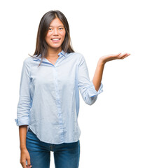 Young asian business woman over isolated background smiling cheerful presenting and pointing with...