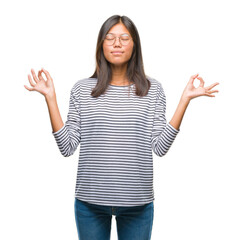Young asian woman wearing glasses over isolated background relax and smiling with eyes closed doing meditation gesture with fingers. Yoga concept.