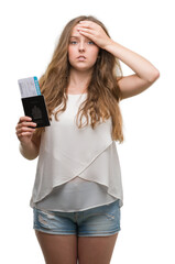 Fototapeta premium Young blonde woman holding passport of canada and boarding pass stressed with hand on head, shocked with shame and surprise face, angry and frustrated. Fear and upset for mistake.