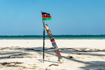The spear of Masai and national flag of Kenya on the background of a beautiful beach landscape. the concept of African tourism.
