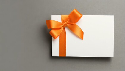 gift card with orange ribbon and bow, a blank white gift card with a vibrant orange ribbon bow right side, a minimalist grey background with subtle shadowing. 