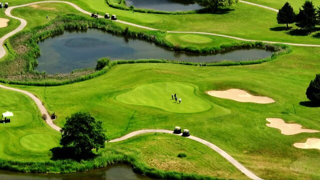 Golf Players Walking On Green Grass Field Near Lake In Newton, Surrey, BC, Canada. aerial shot