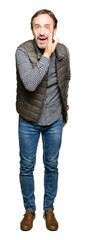 Middle age handsome man wearing winter vest hand on mouth telling secret rumor, whispering malicious talk conversation