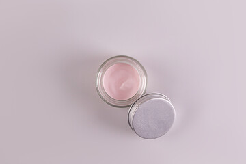 Top view of an open jar of a cosmetic product with a delicate pink texture for everyday face and body skin care. spa. massage. Gray background