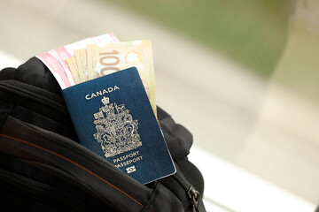 Obraz premium Canadian passport and dollar money bills with airline tickets on backpack close up