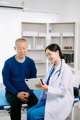 Doctor in white suit take notes while discussing and Asian elderly, man patient who lying on bed with receiving saline solution in hospital .