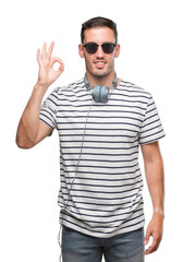 Handsome young man wearing headphones smiling positive doing ok sign with hand and fingers. Successful expression.