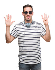 Naklejka premium Handsome young man wearing headphones showing and pointing up with fingers number nine while smiling confident and happy.