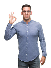 Handsome young elegant man wearing glasses smiling positive doing ok sign with hand and fingers. Successful expression.