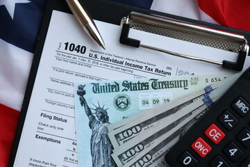 United States 1040 tax form individual income tax return with refund check and US dollar bills close up
