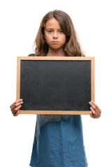 Brunette hispanic girl holding blackboard with a confident expression on smart face thinking serious