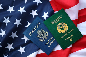 Passport of Nigeria with US Passport on United States of America folded flag close up