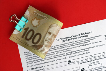 Canadian T2 tax form Corporation income tax return lies on table with canadian money bills close up. Taxation and annual accountant paperwork in Canada