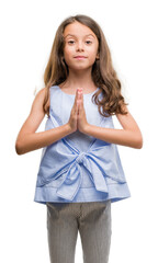 Brunette hispanic girl praying with hands together asking for forgiveness smiling confident.