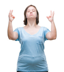 Young adult woman with down syndrome over isolated background relax and smiling with eyes closed doing meditation gesture with fingers. Yoga concept.