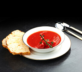 Tomato, soup and bread on menu in restaurant with bowl of healthy food for weight loos diet with nutrition. Dinner, dish and luxury appetizer course in fine dining kitchen with knife and spoon