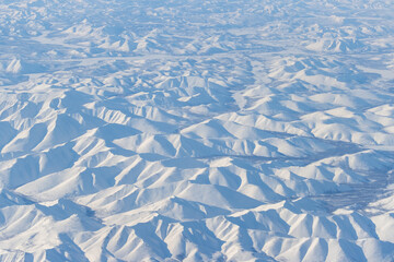 Aerial view of snow-capped mountains. Winter snowy mountain landscape. Air travel to the far North of Russia. Kolyma Mountains, Magadan Region, Siberia, Russian Far East. Great for the background.