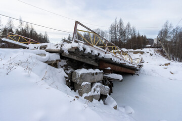 View of the collapsed road bridge. Collapsed bridge over a small river. Fallen damaged bridge. Consequences of an emergency. Cold winter weather. A lot of snow. - 781818033