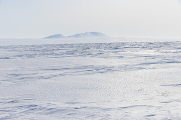 Arctic landscape. View of snow-covered tundra. In the distance are snow-capped mountains. White silence. Cold weather in April. The harsh climate and nature of the polar region. Arctic desert. - 781818085