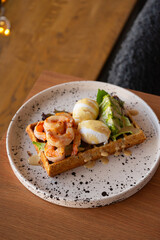Waffle panini with shrimp, eggs Benedict, and avocado