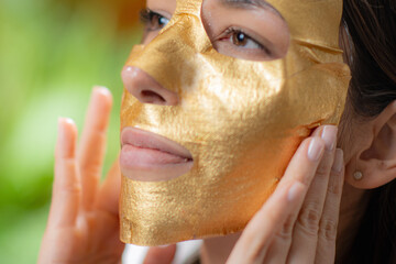 Luxurious gold face mask for radiant skin as a woman applies mask at home - 781826084