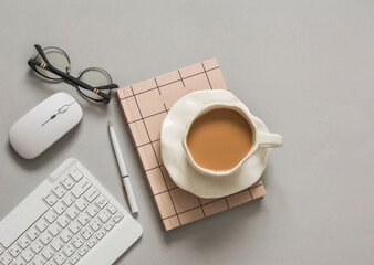 Coffee break in a home office. Work, learning background - keyboard, mouse, notepad, glasses on a gray background, top view - 781826287