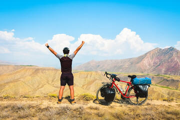 Close up back view inspirational excited joyful caucasian male cyclist on viewpoint by red touring...