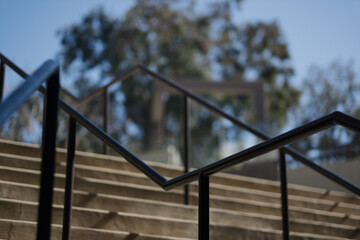 Black handrails provide a geometric composition to a photo looking up across an outdoor staircase...