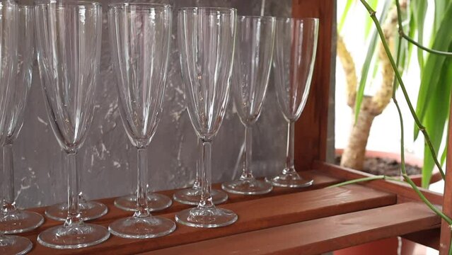 Set of transparent wine glasses on a wooden shelf for guests in room. Keeping lots of glasses on the cupboard close up in shopping center