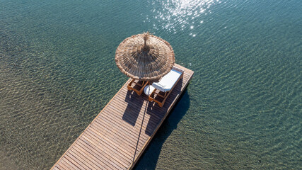 Empty deck sun bed with comfy mattresses on a wooden pier by the tranquil Mediterranean Sea....
