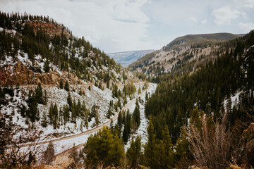Road winding through Rocky Mountains with snow and pine trees