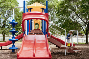 Side View of toddler girl climbing down stairs at playground