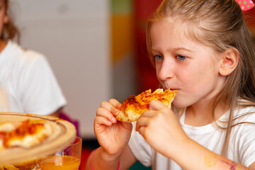 Young Girl Enjoying a Slice of Pizza at a Birthday Party Indoors