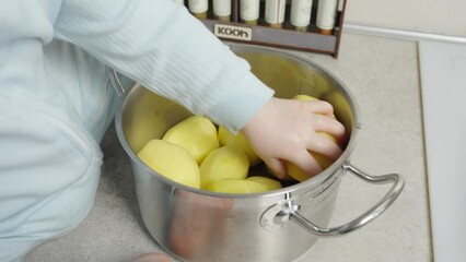 The video shows a child playing with potatoes in a pot, developing motor skills and imagination. Suitable for children's educational videos and toy commercials.